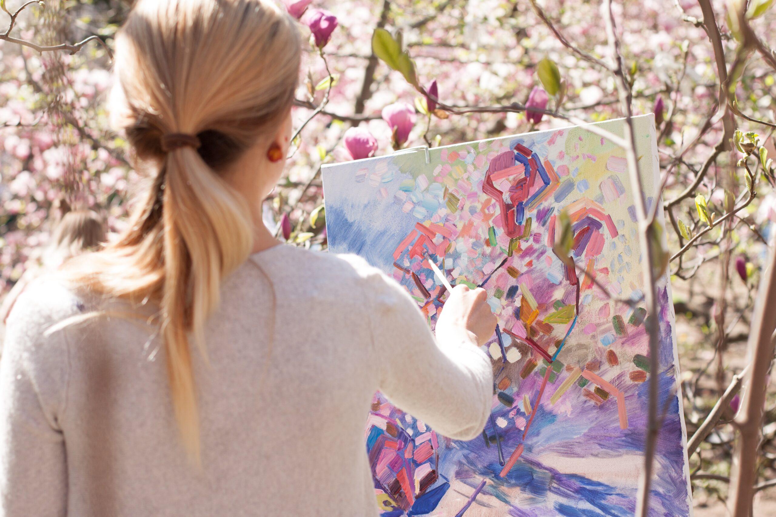 Photo: Female artist painting a nature scene.